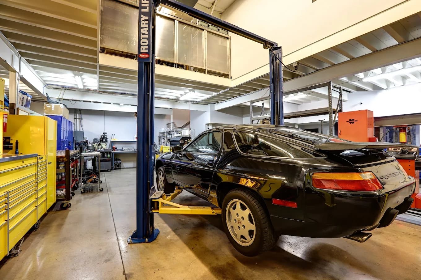 A black Porsche 928 GT on a lift in the Exotic Motorwerks workshop