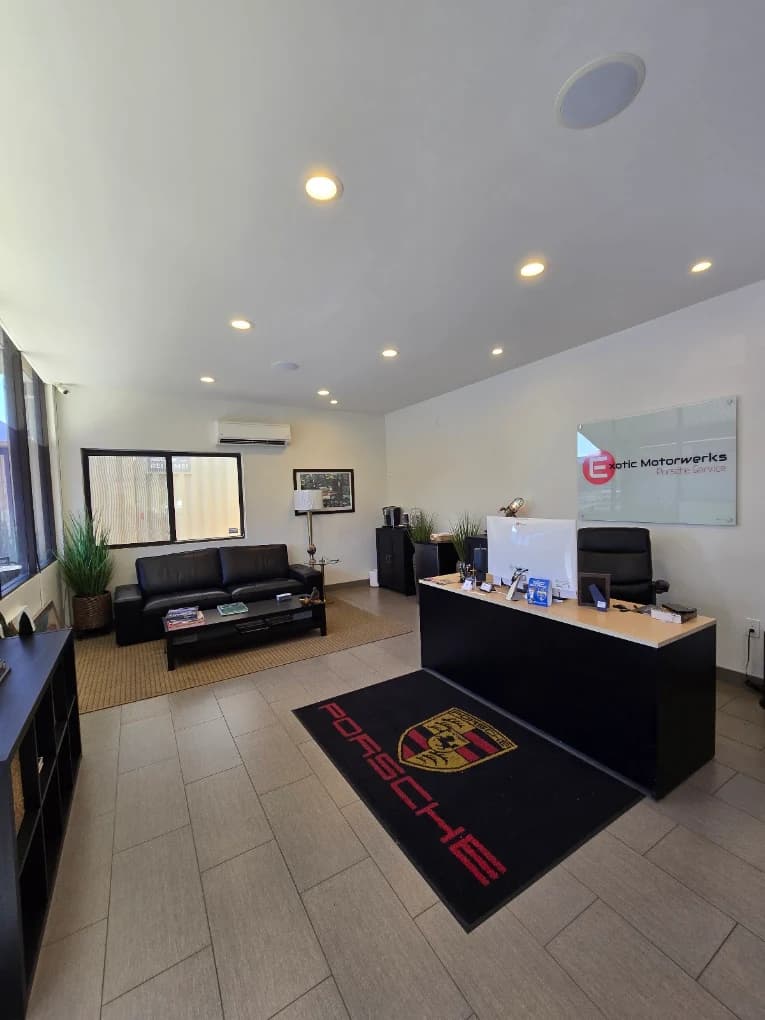 The customer reception at Exotic Motorwerks, with seating, the service desk and the shop's own sign on the wall