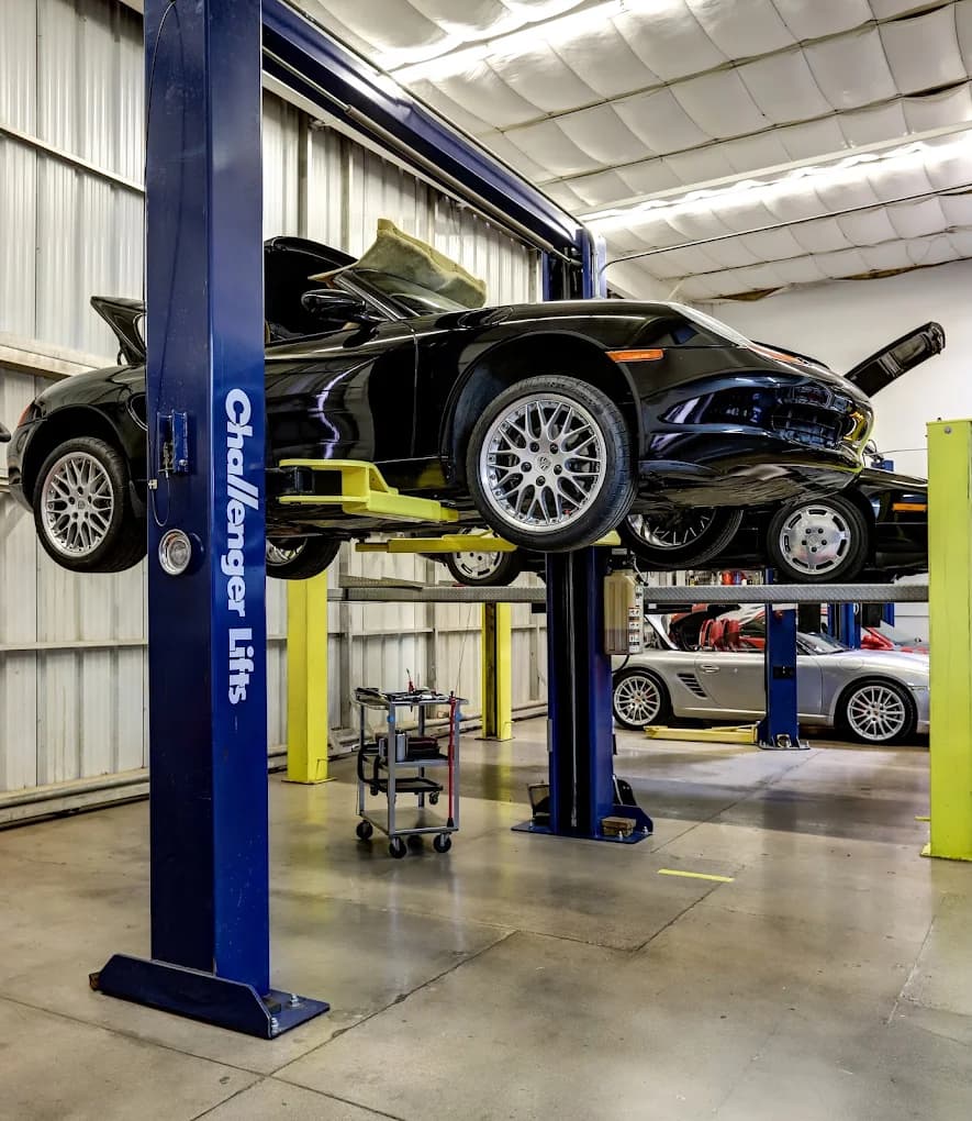 A Porsche 911 raised on a two-post lift in the Exotic Motorwerks service bay