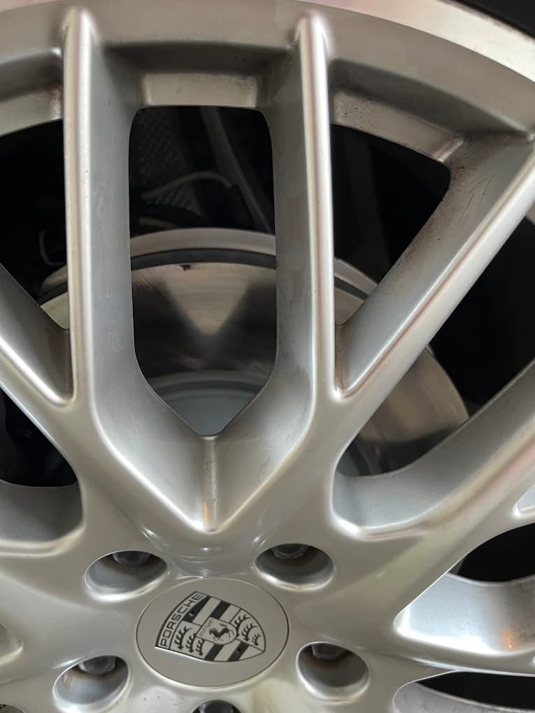 A Porsche alloy wheel with the brake disc and caliper visible through the spokes.